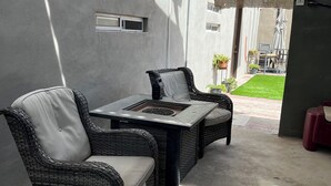 Une terrasse extérieure avec des meubles en osier, un foyer et un sol en béton.