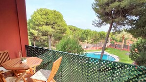 A balcony with a view of a swimming pool, surrounded by greenery and trees. - Pool and terrace Santa Catalina beach (El Puerto de Santa María)
