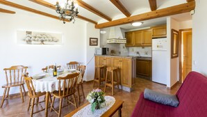 A dining area with wooden chairs and a table set for six, a kitchen with wooden cabinets, and a red sofa in the foreground. - CARREBAIX II - Wonderful apartment with free WiFi. (Orba)