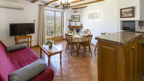 A living room with a red sofa, a TV, a dining table with chairs, a kitchen area with a microwave, and a balcony with a view. - CARREBAIX II - Wonderful apartment with free WiFi. (Orba)
