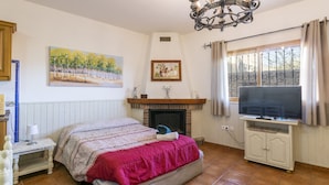 A bedroom with a bed, a television, a fireplace, and artwork on the walls. - CARREBAIX V - Cosy studio with free WiFi. (Orba)