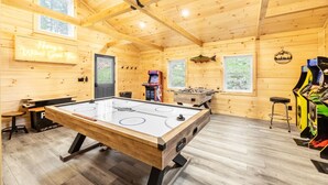 Un interior de madera con una mesa de fútbol de mesa, una mesa de billar y una zona de bar.
