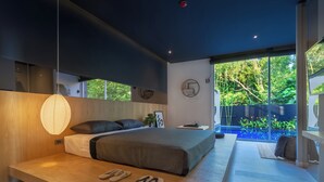 A modern bedroom with a large bed, a bedside table, a hanging light, and a view of a swimming pool. - Villoft Zen Living (Choeng Thale)