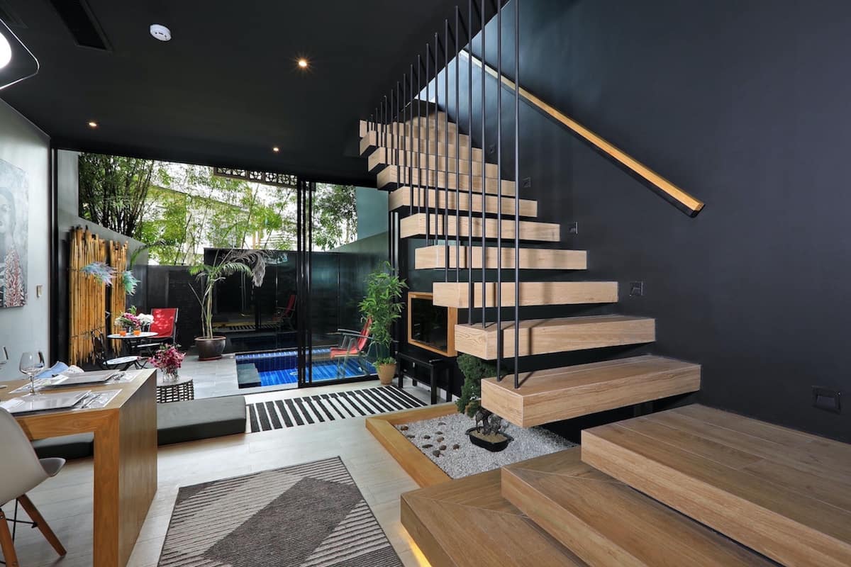 Un interior moderno con una escalera de madera, un comedor y vistas a una piscina.
