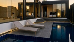A modern house with a swimming pool, lounge chairs, and a bedroom visible through large glass windows. - Villoft Zen Living (Choeng Thale)