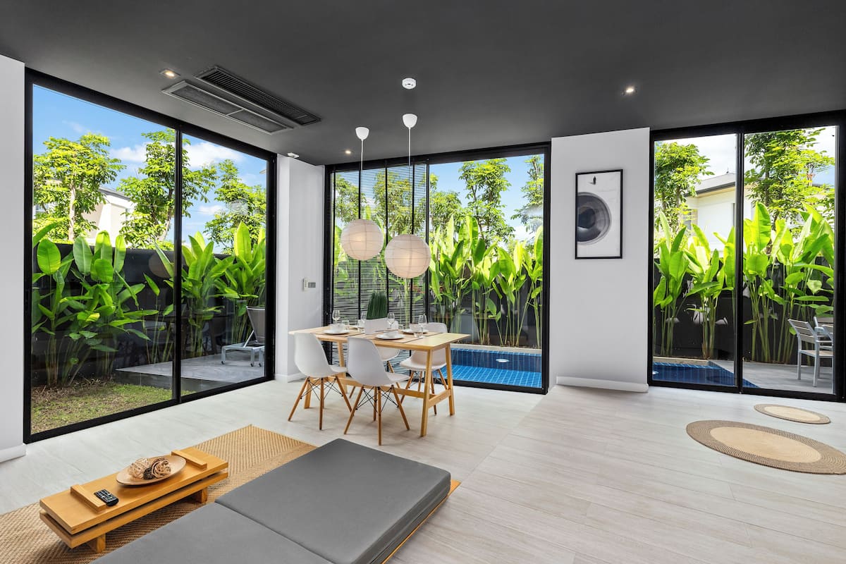 Una sala de estar moderna con comedor, ventanas amplias y vista a una piscina.