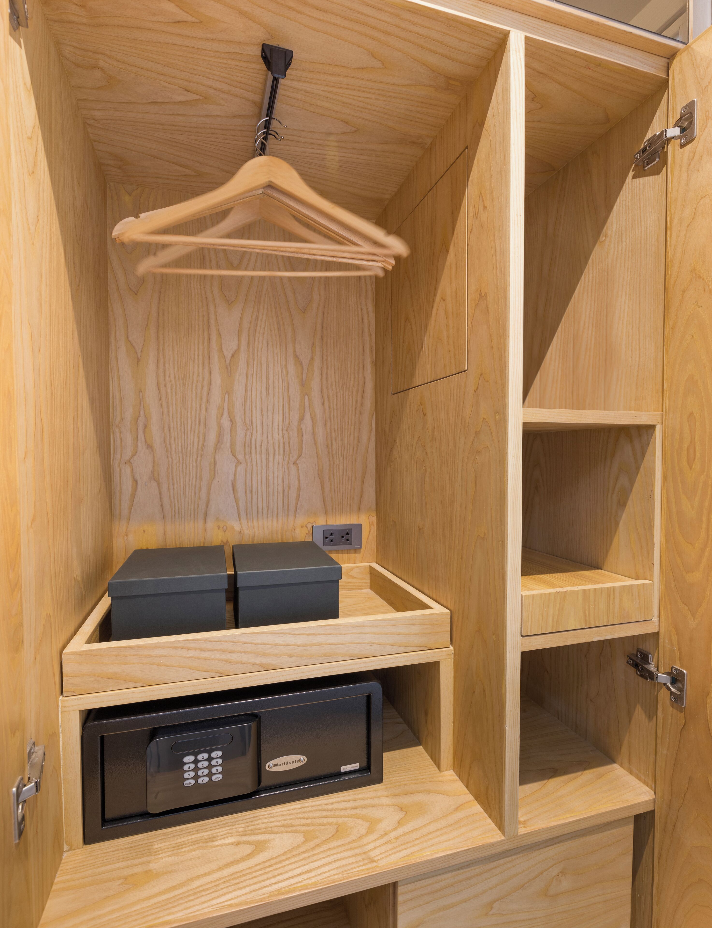 A wooden cabinet with a hanging rack, a black safe, and a shelf.