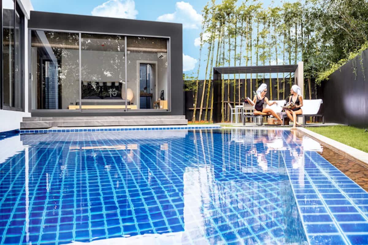 Una casa moderna con piscina, un área de estar al aire libre techada y vistas a árboles.