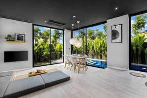 A modern living room with a dining area, large windows, and a pool view.