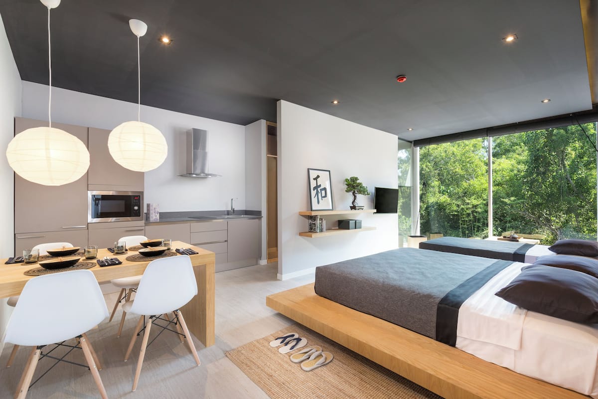 Un dormitorio moderno con una cama grande, mesitas de noche y vistas a zonas verdes a través de amplios ventanales.