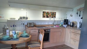 Una cocina compacta con una mesa de madera, sillas, un tostador, un lavabo y una cafetera.