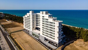 A multi-story hotel with a modern architectural design, located near a coastline with a clear view of the sea. - PINEART LABEL (Gangneung)