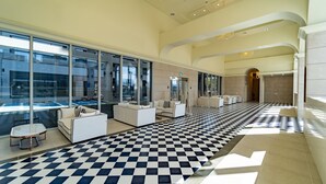 A spacious lobby with a checkered floor, modern seating, large windows, and a view of the outside. - PINEART LABEL (Gangneung)