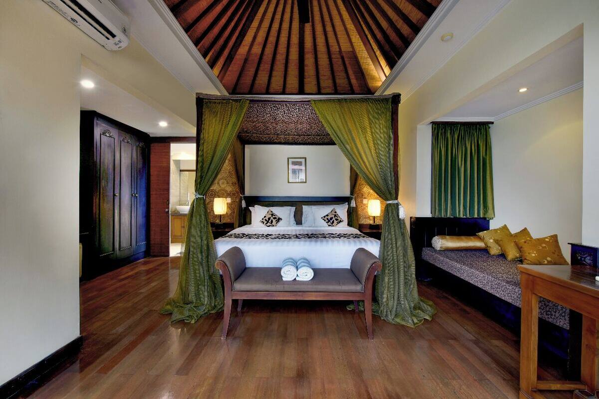 A bedroom with a canopy bed, a bench, and a sofa.