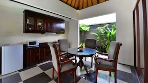 A dining area with a checkered floor, wooden chairs, a round table, and a microwave on a cabinet. - The Khayangan Dreams Villa Seminyak  (Seminyak)
