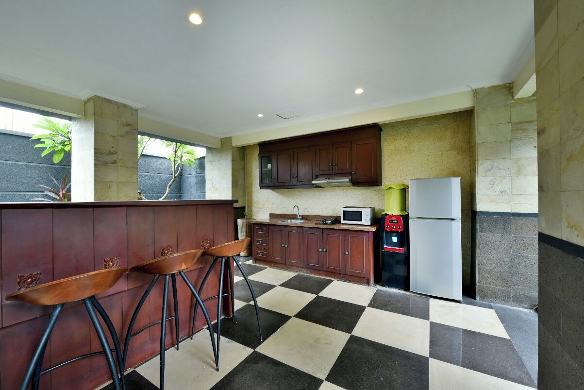 A kitchen with a checkered floor, wooden cabinets, a microwave, and a refrigerator.