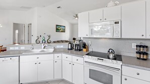 A modern kitchen with white cabinets, a built-in oven, a microwave, and a kettle on the countertop. - Cheerful & Vibrant Home Near Mineral Springs (North Port)