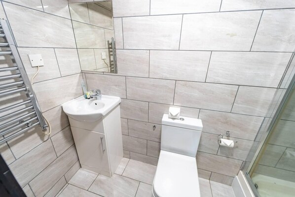 A modern bathroom with a toilet, sink, and glass shower enclosure.