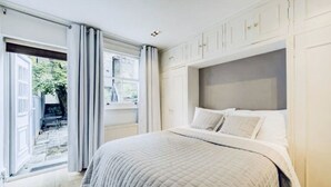 Une chambre avec un grand lit, une fenêtre avec des rideaux et une vue sur l’extérieur.
