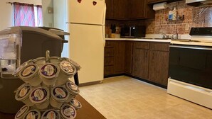 Een keuken met houten kastjes, een witte koelkast, een magnetron en een fornuis.
