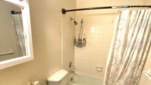 Een badkamer met toilet, wastafel, douche en bad.