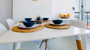 Una mesa de comedor con cuencos azules, individuales tejidos y un espejo tejido en la pared.