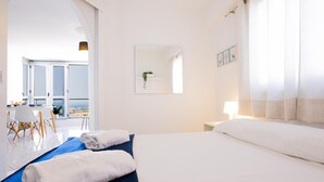 Habitación de hotel con una cama grande, un escritorio con silla, una ventana con vistas y una puerta que da a un balcón.