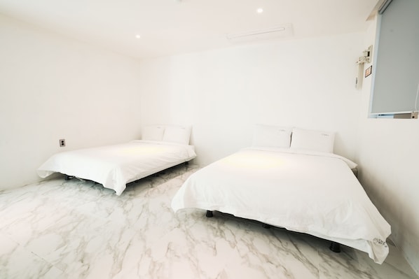 Quarto com duas camas, roupa de cama branca e chão de mármore.