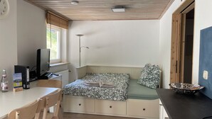 A compact room with a bed, a desk, a chair, a television, and a window.