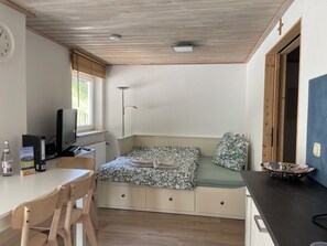 A compact room with a bed, a desk, a chair, a television, and a window.