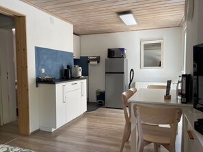 Una cucina moderna con mobili bianchi, una parete blu a contrasto, un forno a microonde e un frigorifero.