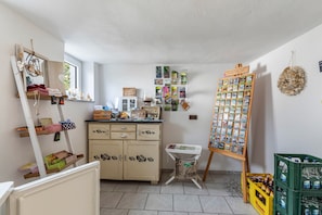 Una habitación con un aparador de madera, un espejo, una mesita con cartas y un cesto verde.