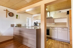 Una cocina moderna con una isla de madera, electrodomésticos de acero inoxidable y techo de madera.