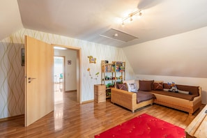 Una sala de estar acogedora con un sofá, una estantería y una puerta de madera que da a otra habitación.