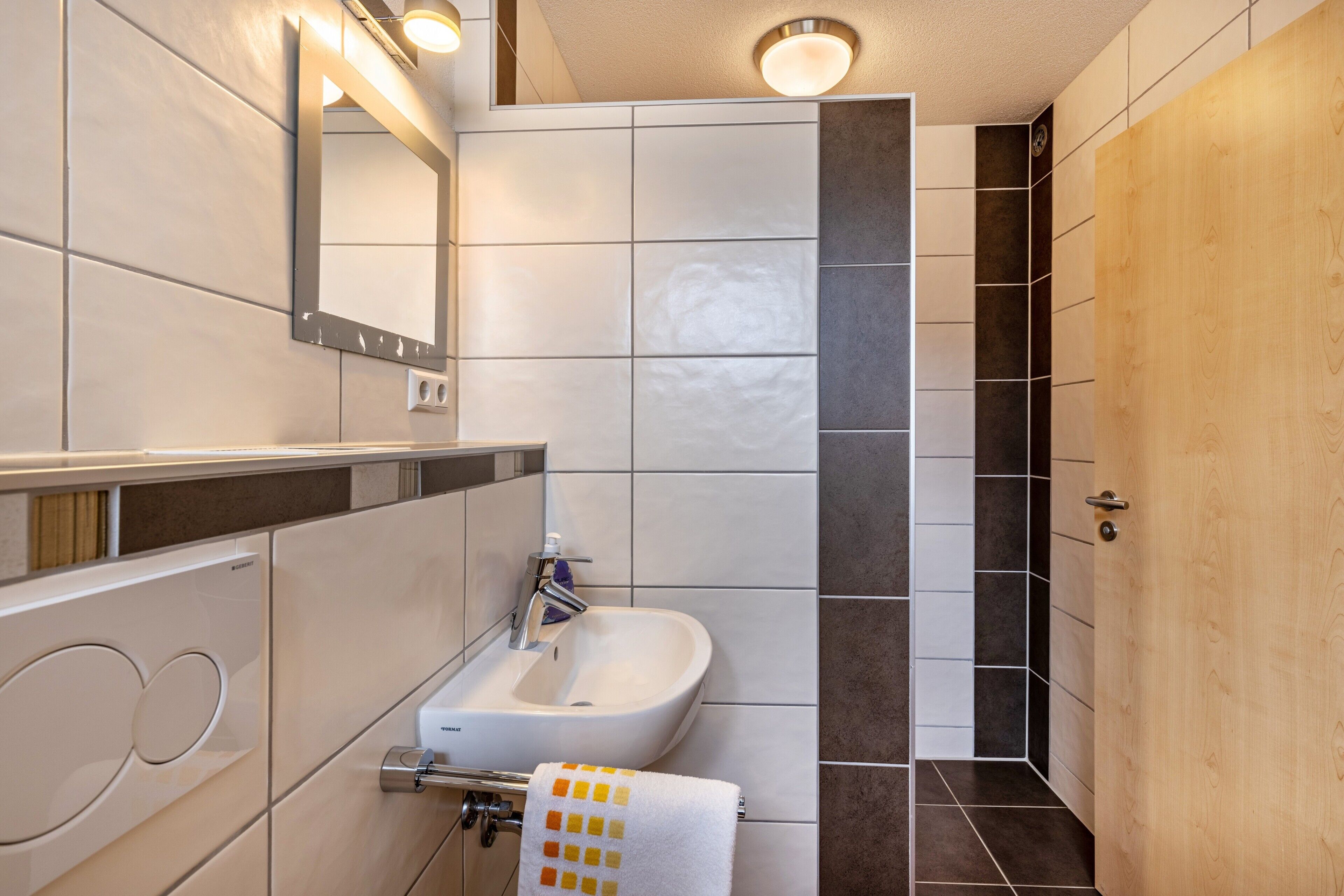 Casa de banho moderna com lavatório, espelho e chuveiro.
