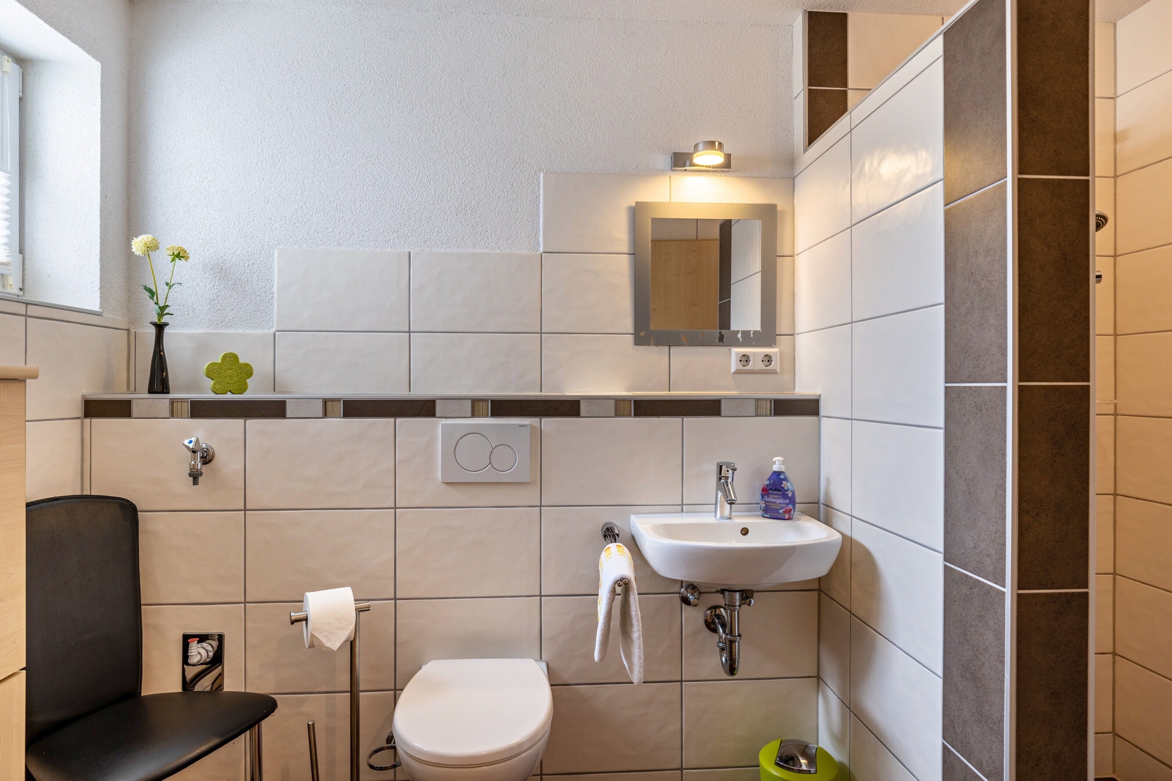 A bathroom with a toilet, sink, mirror, and towel rack.