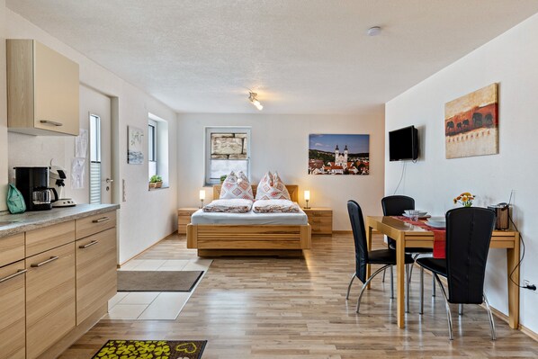 Une chambre moderne équipée d’un lit, d’une table à manger, d’un téléviseur et d’un coin cuisine.
