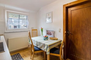 Un espace repas comprenant une table, des chaises, une fenêtre, un radiateur et une porte.