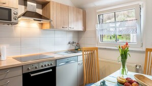 Cocina moderna con lavavajillas, horno y microondas. Hay una ventana con vistas a zonas verdes.