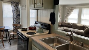 A compact kitchen with a stove, sink, and a dining area with a table and chairs. - One-Bedroom Apt in Hampton NH! (Hampton)