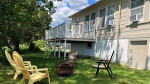 A house with a covered porch, outdoor seating, and a fire pit. - One-Bedroom Apt in Hampton NH! (Hampton)