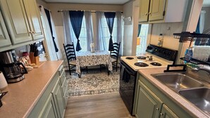 A kitchen with a dining area, featuring light green cabinets, a patterned rug, and a stove. - One-Bedroom Apt in Hampton NH! (Hampton)