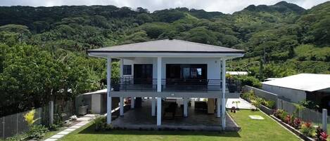 A two-story house with a flat roof, a covered patio, and a well-maintained lawn.