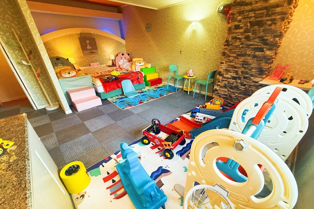 A playroom with a soft play area, a sofa, and a table with toys.