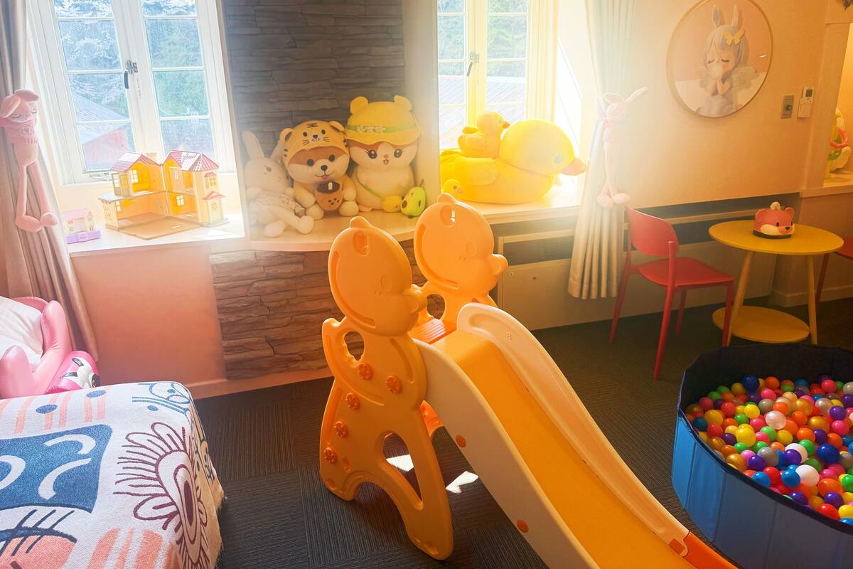 A children's play area with a slide, a ball pit, and various stuffed toys.
