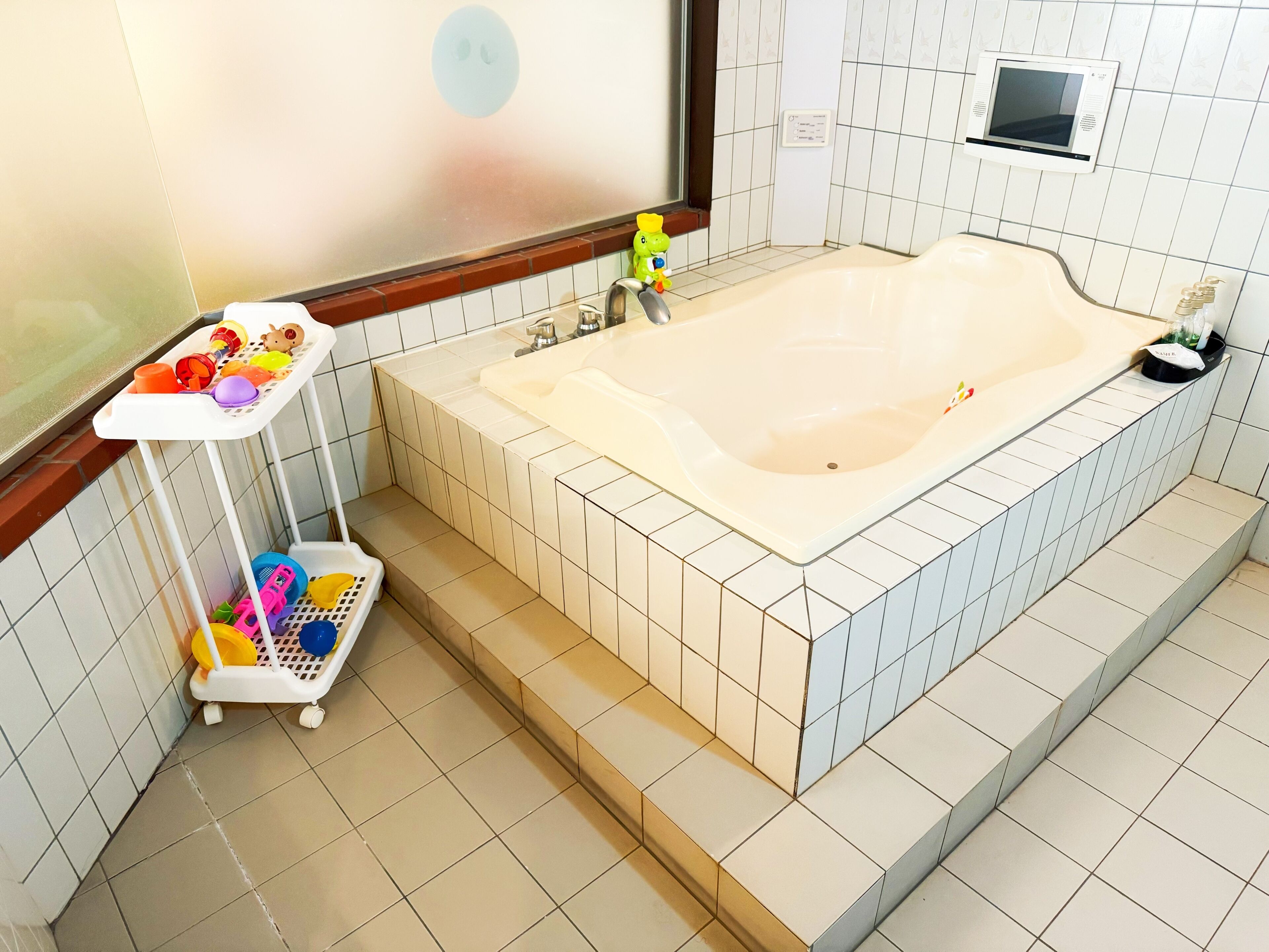 A bathroom with a bathtub, a small shelf with toiletries, and a baby changing station.