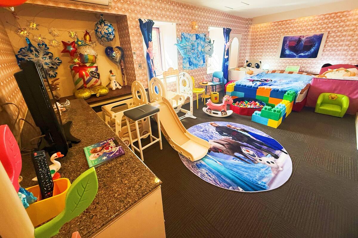 A children's playroom with a play area, seating, and a large window.