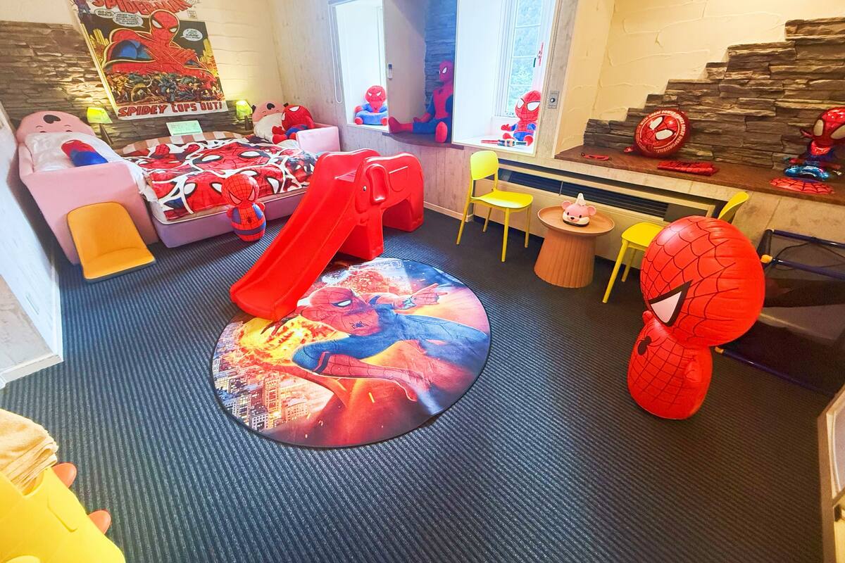 A child's playroom with a slide, Spider-Man themed decorations, and a window with a view.