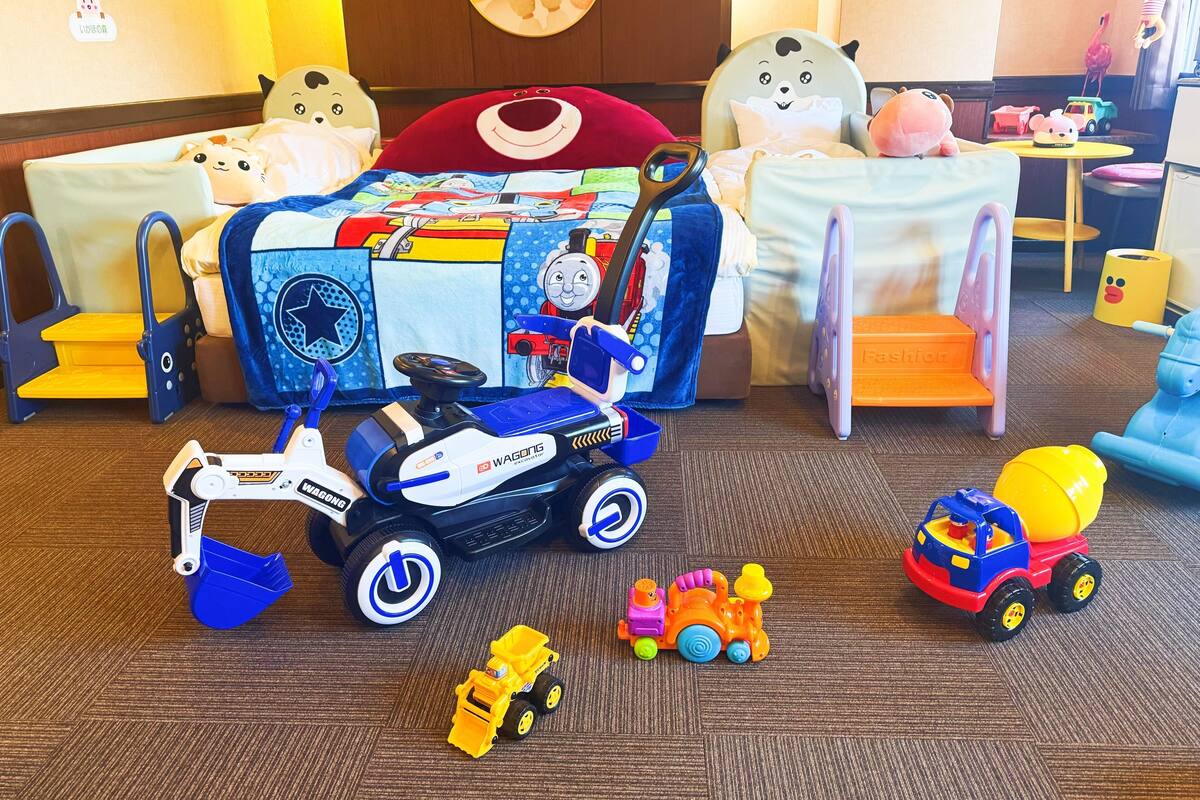 A child's playroom with a bed, a toy train, and various toys.