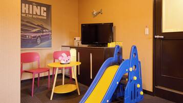 A children's play area with a slide, a small table with a toy, and a TV in the corner.